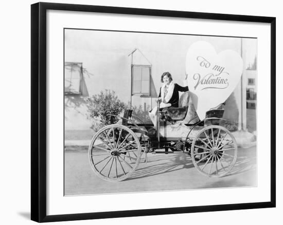 Young Woman Sitting on a Car Holding a Big Heart Shaped Sign-null-Framed Photo