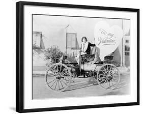 Young Woman Sitting on a Car Holding a Big Heart Shaped Sign-null-Framed Photo