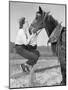 Young Woman Sitting on a Fence and Feeding Her Horse-null-Mounted Photo