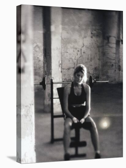 Young Woman Sitting on a Weight Bench-null-Stretched Canvas