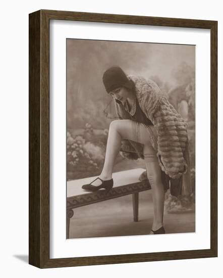 Young Woman Wearing a Fur Coat Cloche Hat and T-Bar Shoes Lifts Her Leg Up-null-Framed Photographic Print