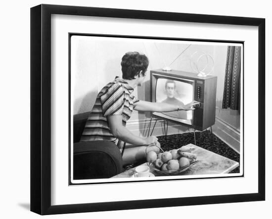 Young Woman with Short Dark Hair Wearing a Stripy Mini Dress Adjusts Her Television Set-null-Framed Art Print