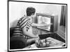 Young Woman with Short Dark Hair Wearing a Stripy Mini Dress Adjusts Her Television Set-null-Mounted Art Print