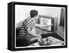 Young Woman with Short Dark Hair Wearing a Stripy Mini Dress Adjusts Her Television Set-null-Framed Stretched Canvas