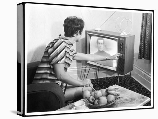 Young Woman with Short Dark Hair Wearing a Stripy Mini Dress Adjusts Her Television Set-null-Stretched Canvas