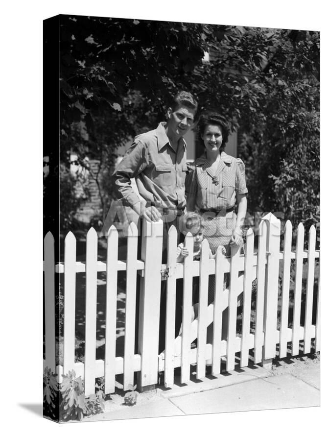 Portrait Of Family In Front Of House With Picket Fence