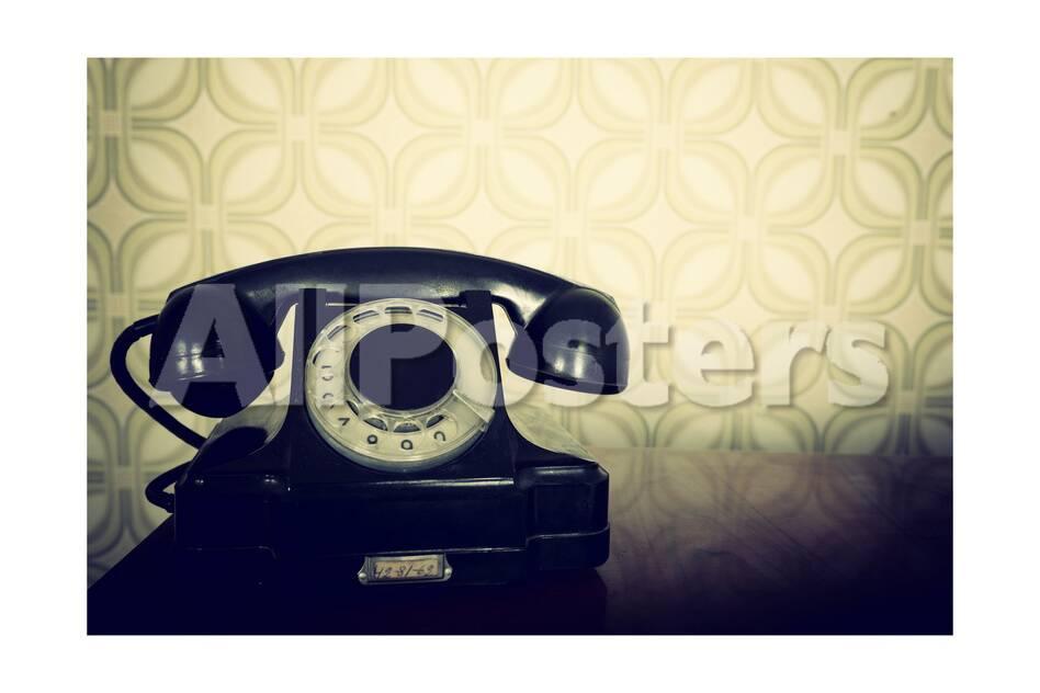 vintage old telephone black retro phone is on wooden table over green old fashioned wallpaper
